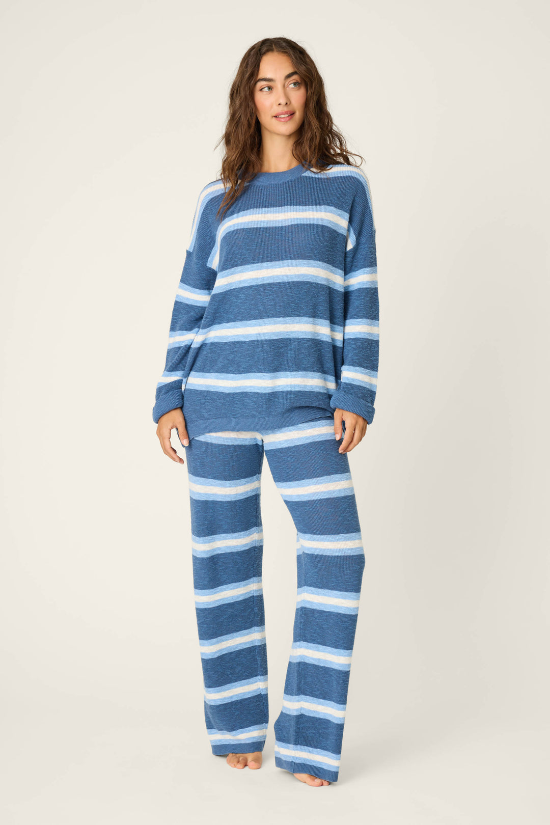 A person stands barefoot against a plain background, wearing the P.J. Salvage More Amour Striped Long Sleeve Top and matching wide-leg pants, creating a comfortable and casual look.