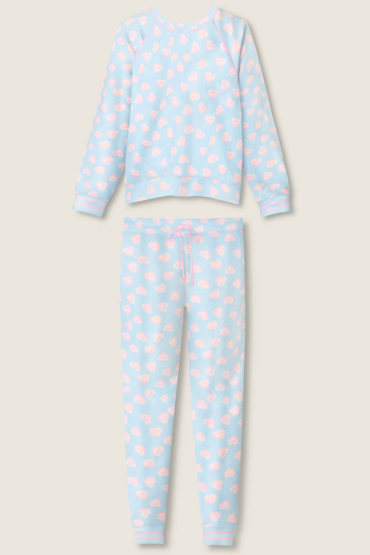 The P.J. Salvage Sweetheart Love Hearts Print Peachy PJ Set includes a long-sleeve top and pants, both in light blue with white cloud and pink heart prints, plus a pink waist drawstring on the pants.