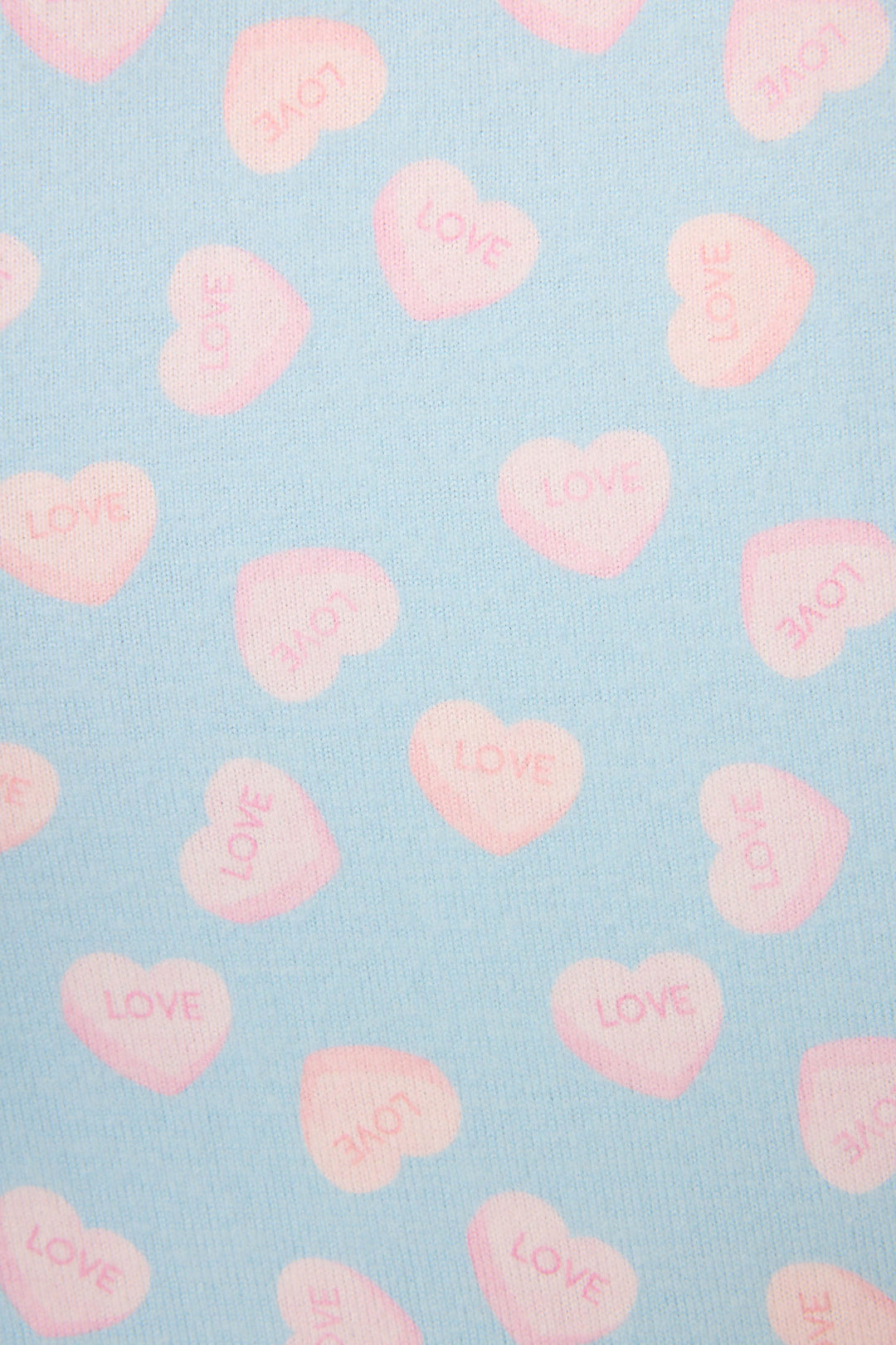 The Sweetheart Love Hearts Print Peachy PJ Set by P.J. Salvage features light blue fabric with pink hearts, each with "LOVE" in bold letters inside. The hearts are evenly spaced and oriented in different directions.