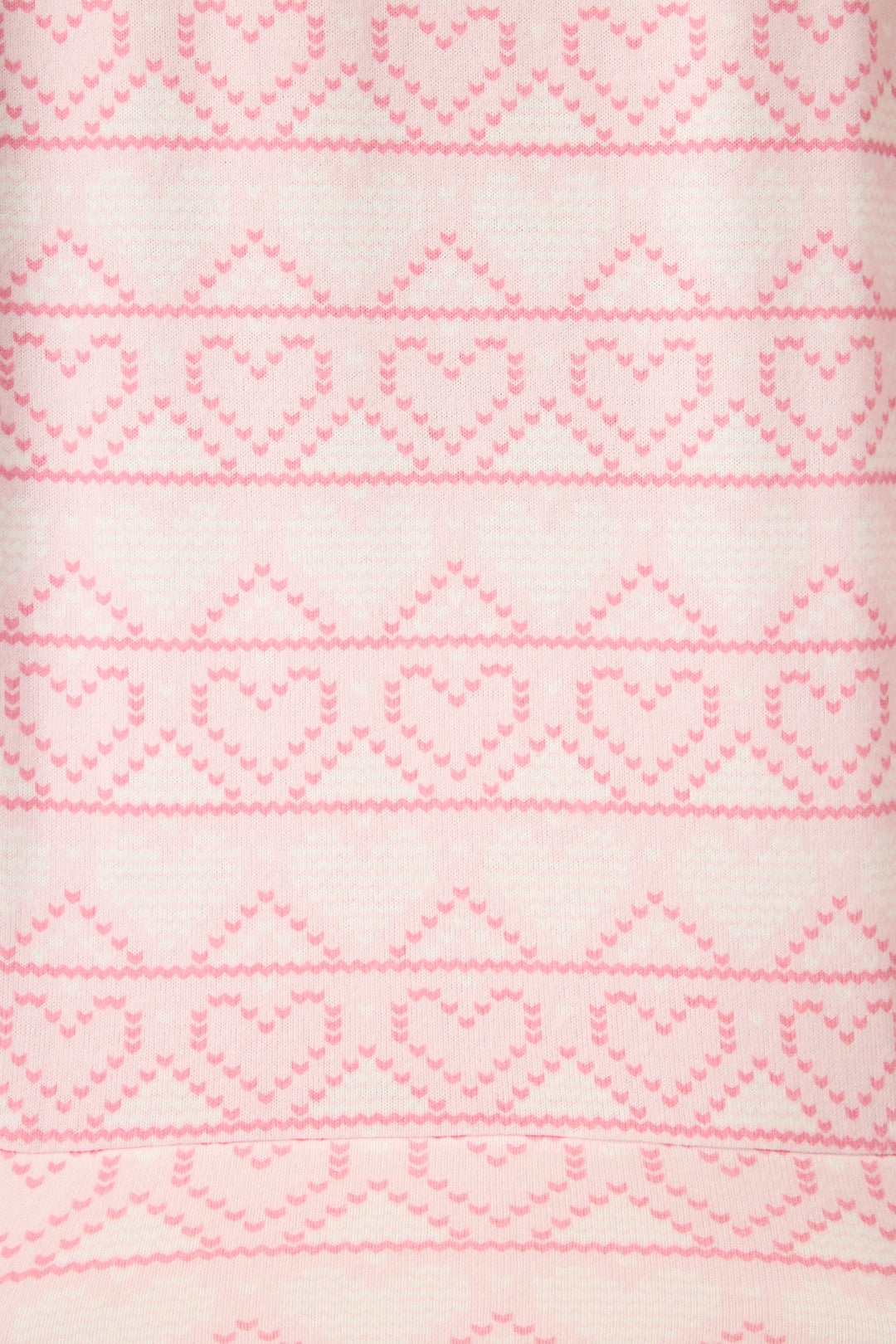 Close-up of the Fairisle Heart Print Peachy PJ Set by P.J. Salvage, showing a light pink and white symmetrical pattern with evenly spaced rows of knitted heart shapes across the soft fabric.