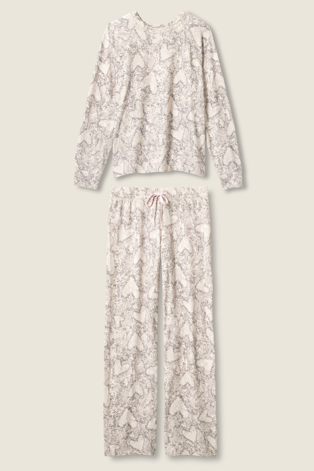 The P.J. Salvage Snakeskin Heart Print Peachy PJ Set includes a long-sleeve top and drawstring pants, both in a light cream base with gray and white snakeskin heart print, laid flat on a neutral background.