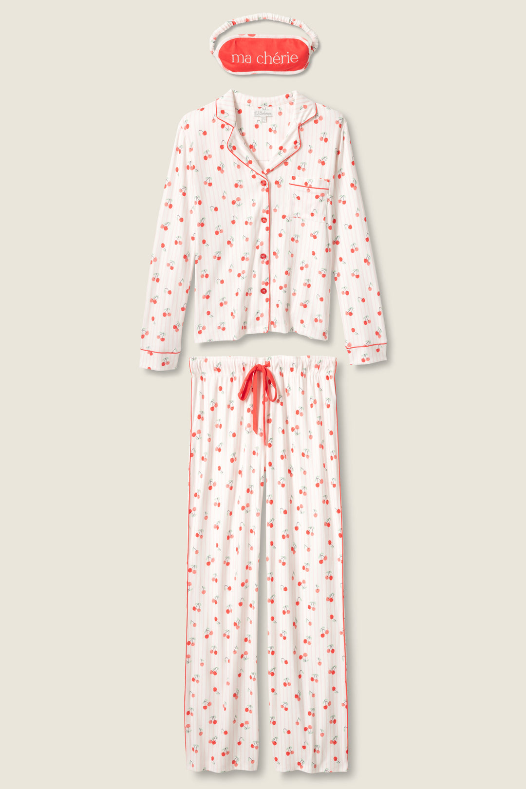 The P.J. Salvage Valentine's Day Cherry Print 3-Piece PJ Set features a white pajama set with red cherry print, a long-sleeve button-up top with red piping and pocket, long pants with red drawstring, and a "ma chérie" sleep mask.