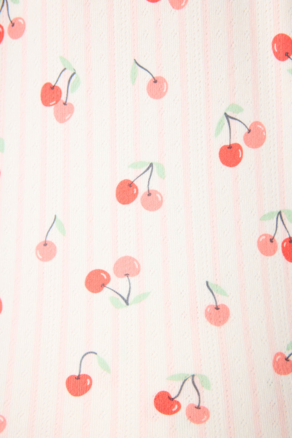 A close-up of the Valentine's Day Cherry Print 3-Piece PJ Set by P.J. Salvage shows pink and white striped fabric adorned with small red cherries and green stems, creating a playful, festive pattern.