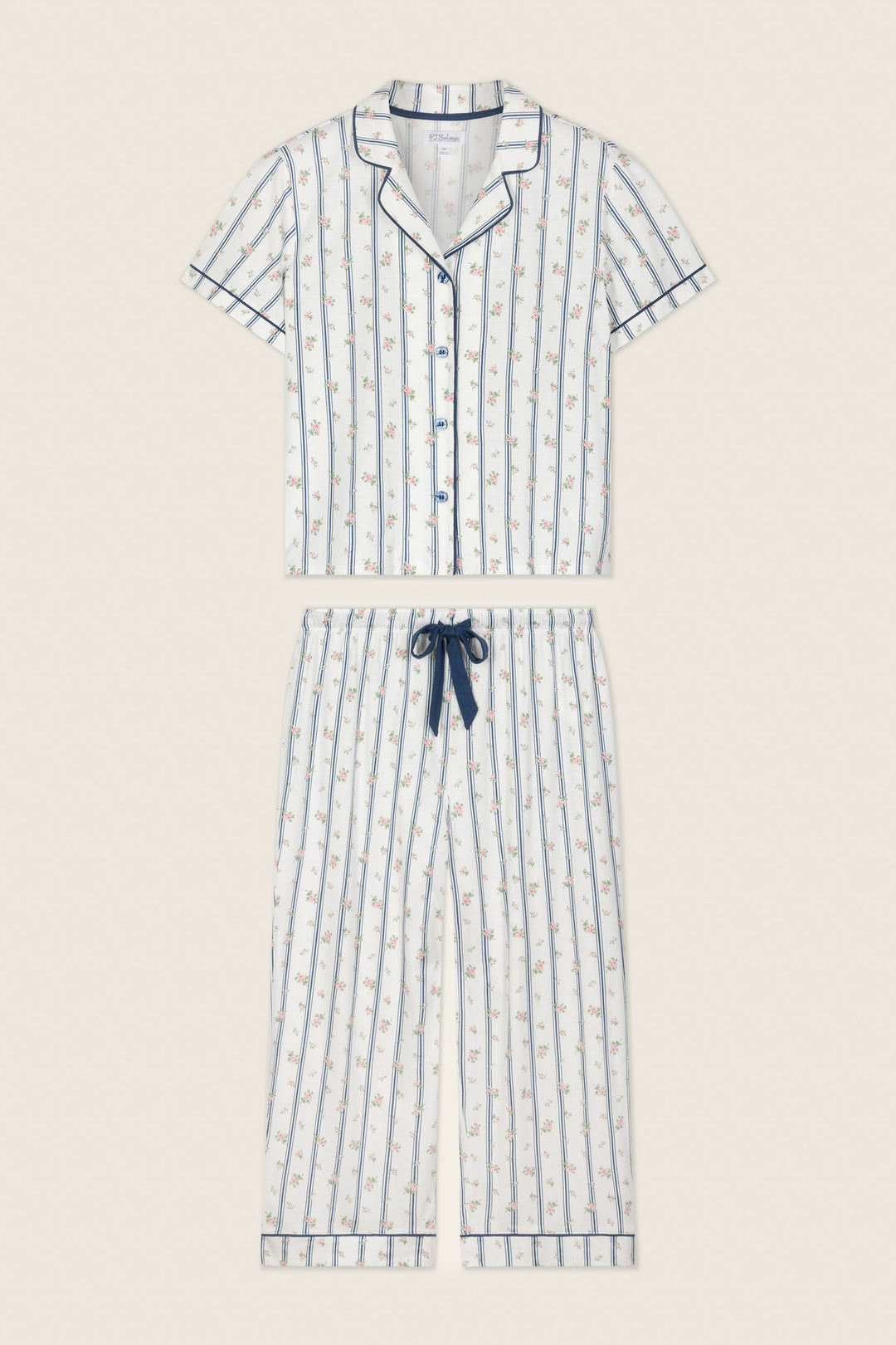 The P.J. Salvage Cotton Jersey Stripes & Blooms Cropped PJ Set features a short-sleeve button-up top and drawstring pants in white with vertical blue stripes, floral print, and navy piping along the edges.