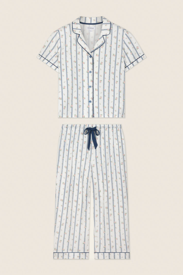 The P.J. Salvage Cotton Jersey Stripes & Blooms Cropped PJ Set features a short-sleeve button-up top and drawstring pants in white with vertical blue stripes, floral print, and navy piping along the edges.