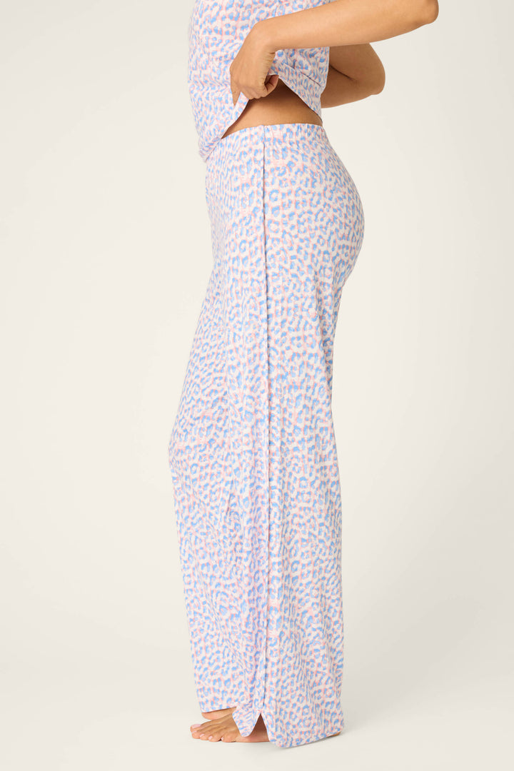 A person stands barefoot against a plain off-white background, wearing P.J. Salvage Animal Lover Leopard Print Open Leg Pants and a matching top. The waistband of the pants is visible as the top is lifted slightly.