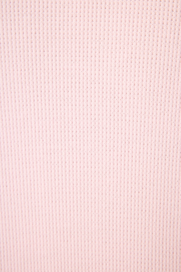 A close-up of the Cross Stitch Casuals Ballet Pink Lounge Set by P.J. Salvage shows its light pink fabric with a vertical ribbed texture and fine, evenly spaced lines.