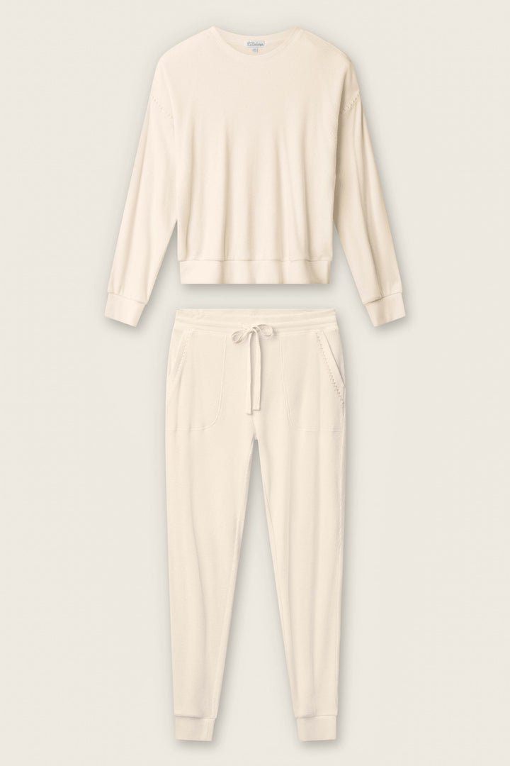 The P.J. Salvage Cross Stitch Casuals Light Beige Lounge Set features a long-sleeve crew neck top and drawstring jogger pants with pockets, shown laid flat on a neutral background.