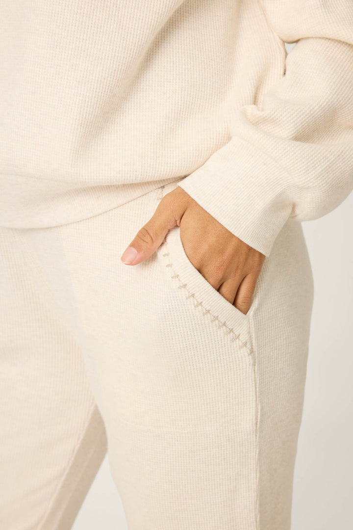 Someone wearing the P.J. Salvage Cross Stitch Casuals Light Beige Lounge Set has their right hand in the pants pocket, highlighting the visible stitching along the pocket’s edge.