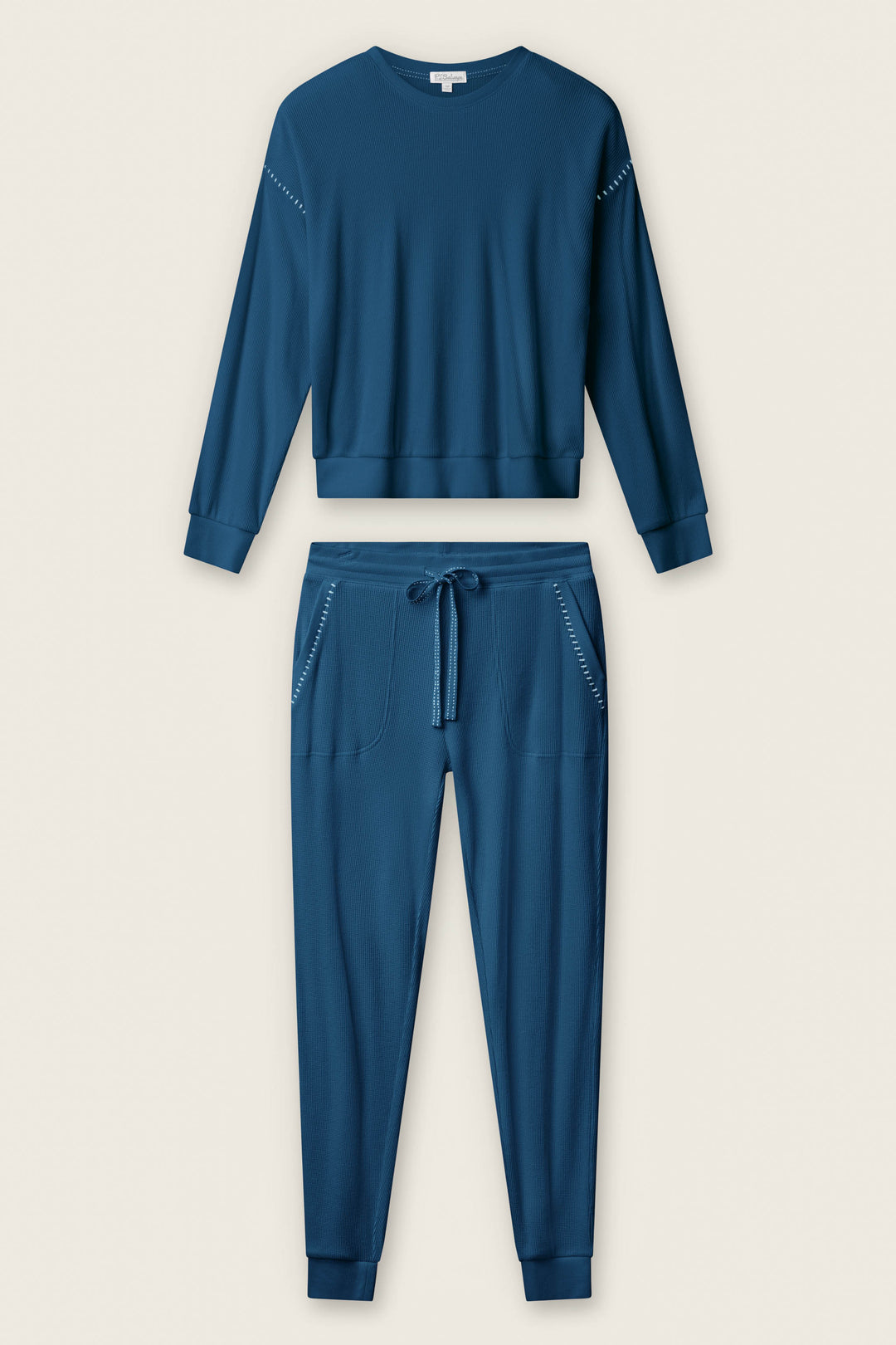 The P.J. Salvage Cross Stitch Casuals Navy Lounge Set features a long-sleeve sweatshirt with ribbed cuffs and drawstring jogger pants with side pockets and elastic cuffs, displayed on a neutral background.