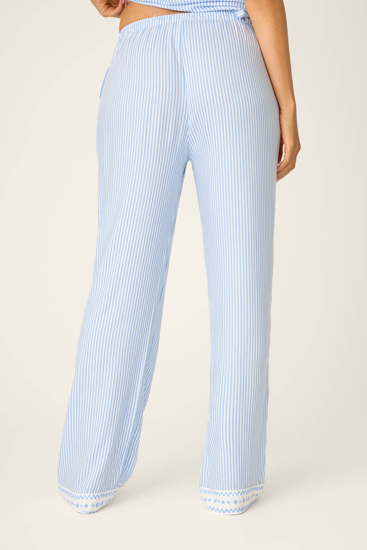 A person is shown from the back wearing P.J. Salvage Frutta Fresca Striped Open Leg Pants—blue-and-white striped sleepwear with a relaxed, straight-leg fit and decorative trim at the hem for added charm.