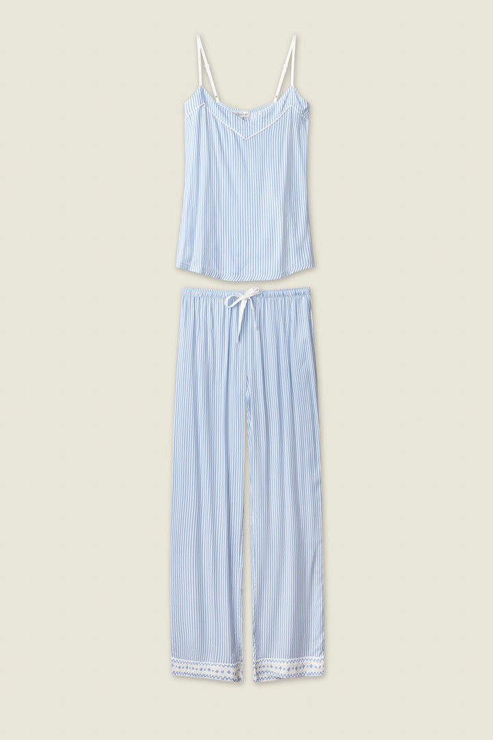 The P.J. Salvage Frutta Fresca Striped Long Lounge Set features thin blue and white stripes, a sleeveless spaghetti strap top, and matching drawstring pants with lace-trimmed hems, shown laid flat on a light beige background.