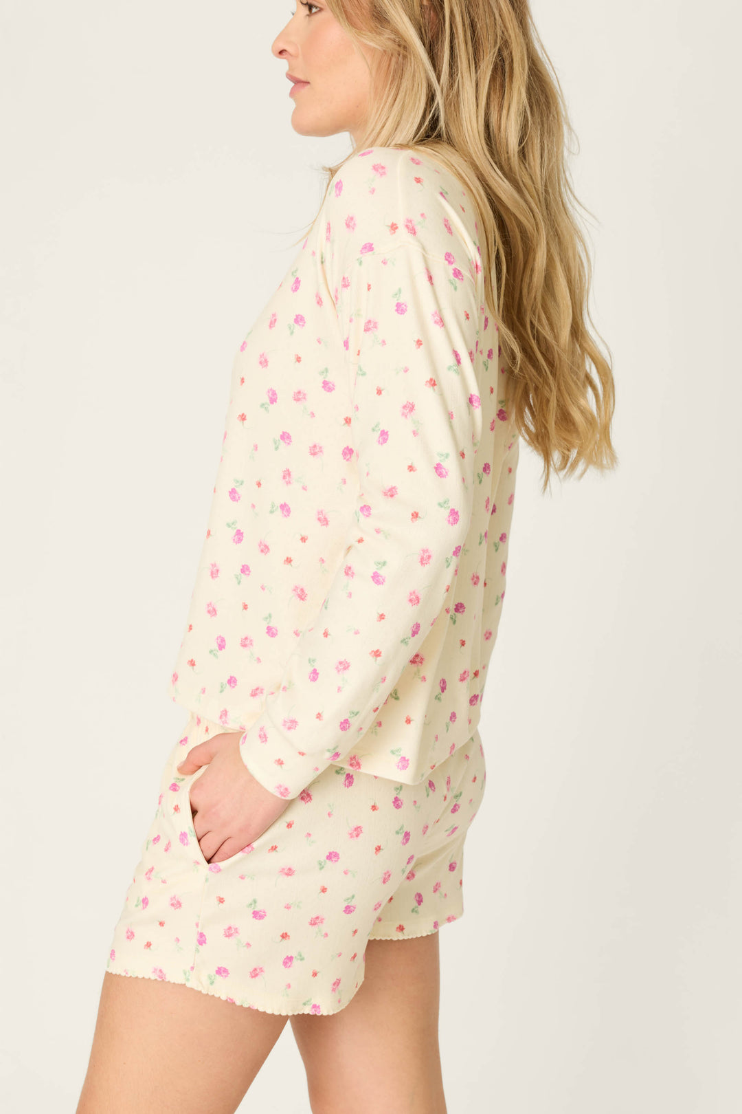 A woman with long blonde hair is shown from the side, wearing the P.J. Salvage For the Mamas Butter Blooms Long Sleeve Top in butter yellow pointelle. The background is plain and light-colored.