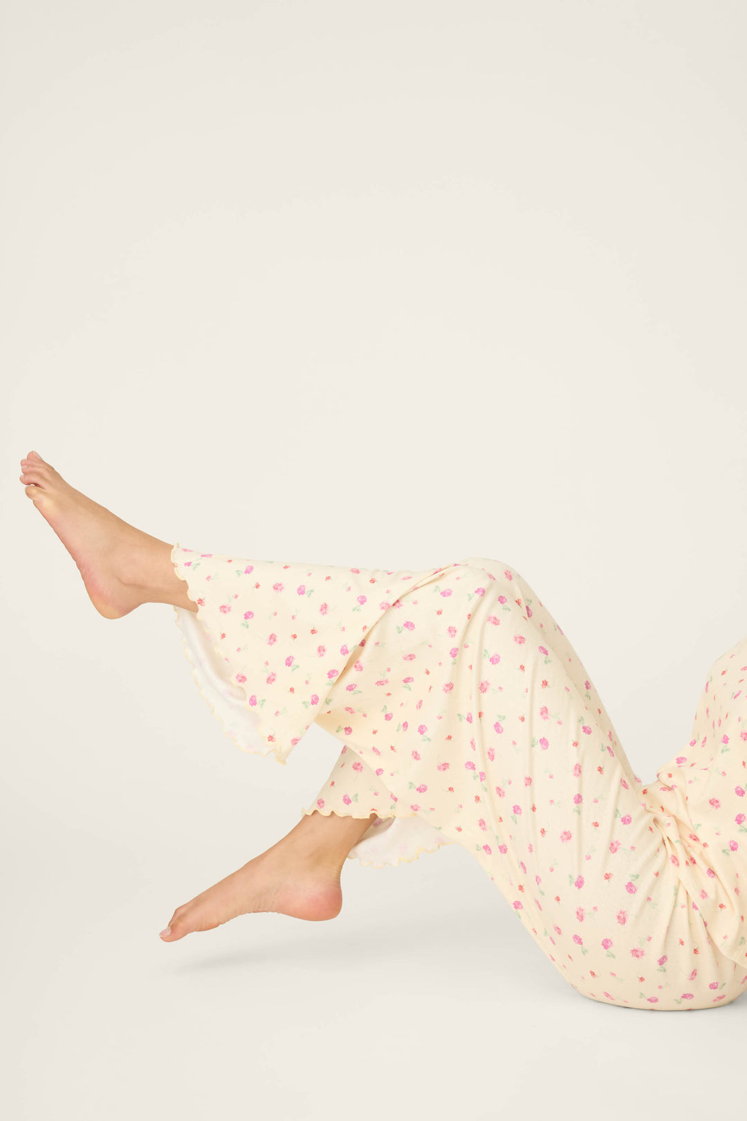 Someone wearing P.J. Salvage's For the Mamas Butter Blooms Open Leg Pajama Pants is lying down with legs bent and feet up, set against a plain light background.