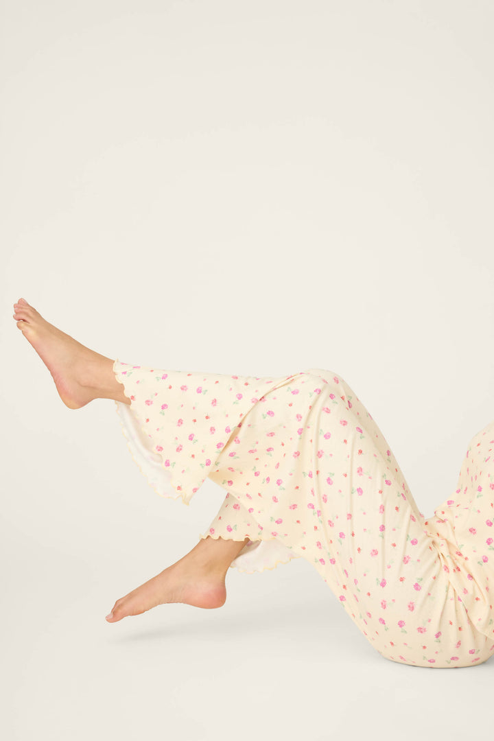 Someone wearing P.J. Salvage's For the Mamas Butter Blooms Open Leg Pajama Pants is lying down with legs bent and feet up, set against a plain light background.