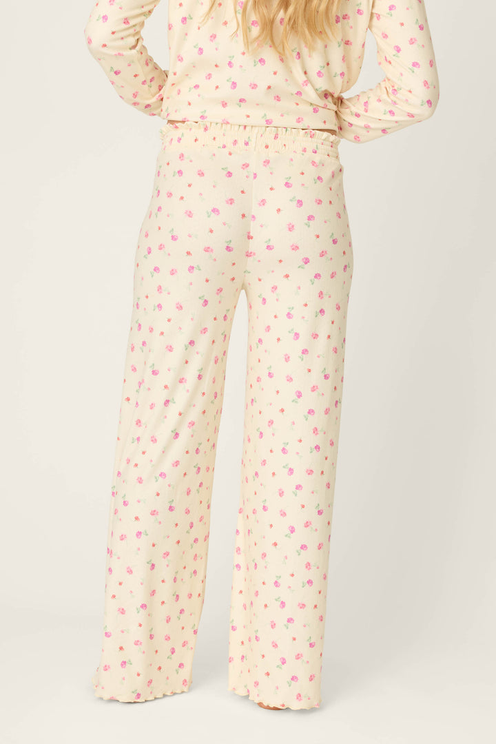 A person is seen from the back wearing P.J. Salvage For the Mamas Butter Blooms Open Leg Pajama Pants in a cream floral print with pink accents; a matching long-sleeve top is partly visible against a plain light background.
