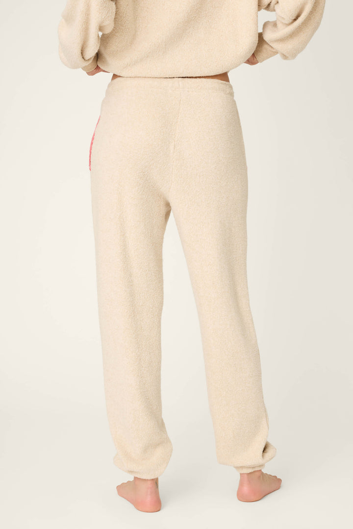 A person stands barefoot facing away, wearing P.J. Salvage For the Mamas Sweetheart Banded Pants in a plush oatmeal fabric. Only their lower half and part of their arms show against a plain, light background.
