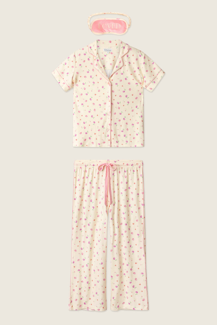The P.J. Salvage For the Mamas Butter Blooms Cropped 3-Piece PJ Set includes a short-sleeved floral top, matching pants, and a pink “LOVED” sleep mask—offering cozy pointelle comfort for relaxing at home.