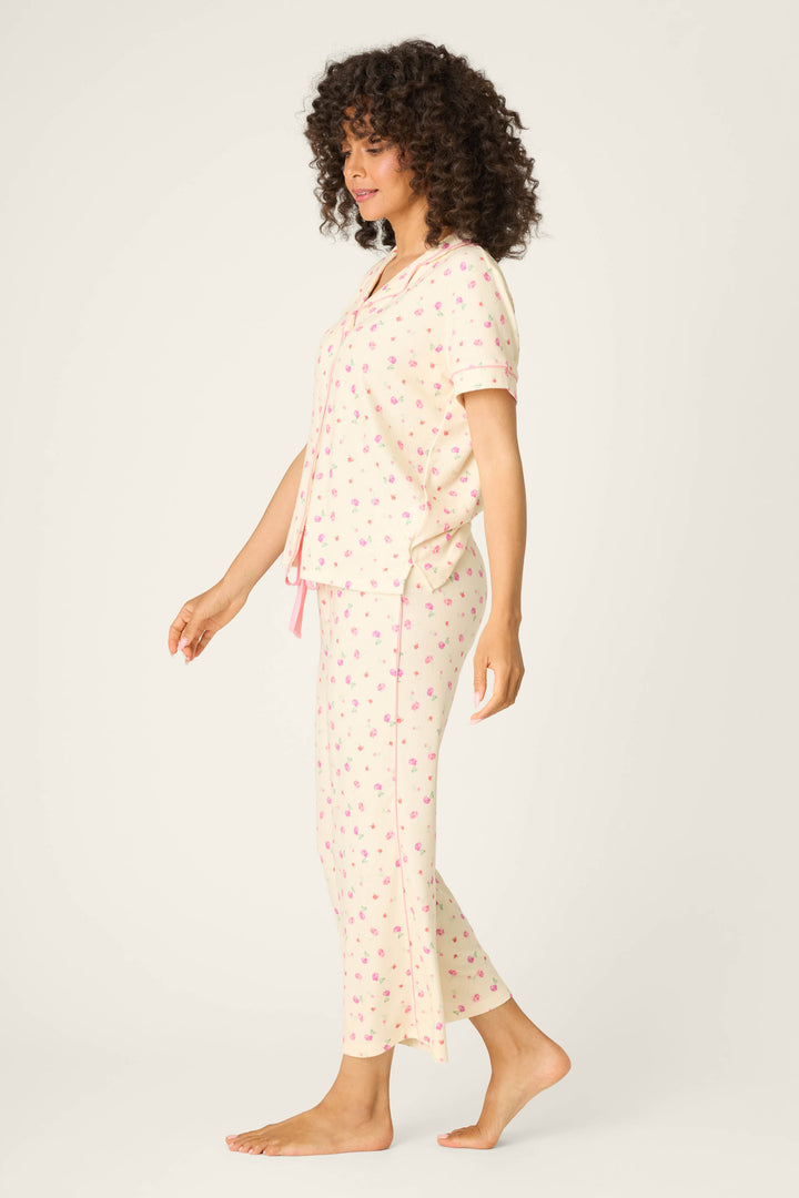 A woman stands barefoot against a plain background, wearing the P.J. Salvage For the Mamas Butter Blooms Cropped 3-Piece PJ Set in butter yellow with pink floral pattern and drawstrings, facing sideways with her arms relaxed.