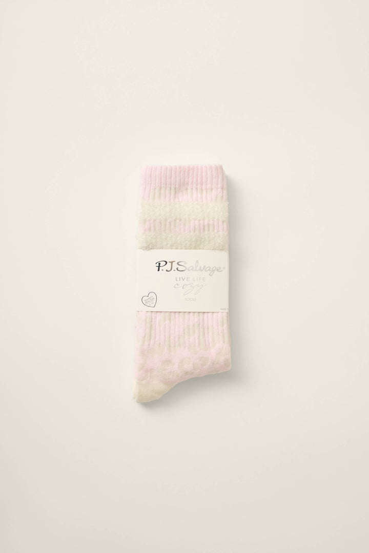A pair of folded Luxe Leopard Dreams Ribbed Crew Socks in ballet-pink and white leopard print, with a white P.J. Salvage “LIVE LIFE COZY” label, rests on a plain light background.