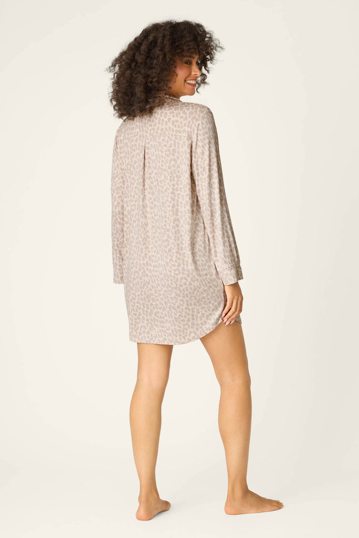 A person with curly hair, wearing the P.J. Salvage Luxe Leopard Dreams Nightshirt, stands barefoot on a light background, turning slightly to the side and looking over their shoulder.