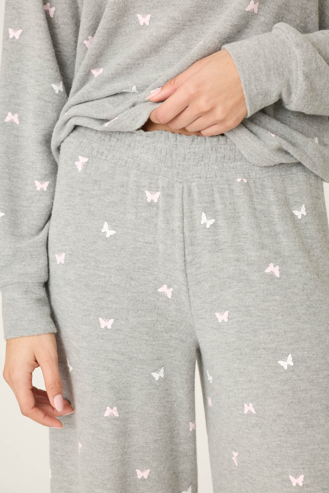 A person wears P.J. Salvage Peachy Mix & Match Butterfly Kisses Open Leg Lounge Pants in light gray with a delicate butterfly print, featuring a comfy elastic waistband for added comfort.