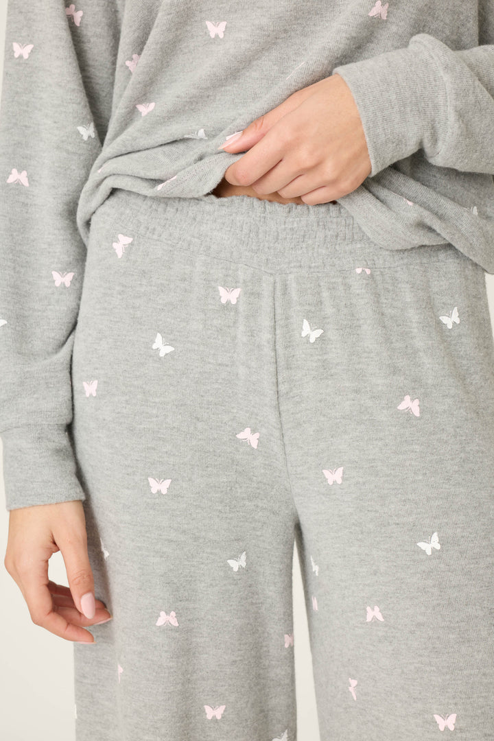 A person wears P.J. Salvage Peachy Mix & Match Butterfly Kisses Open Leg Lounge Pants in light gray with a delicate butterfly print, featuring a comfy elastic waistband for added comfort.