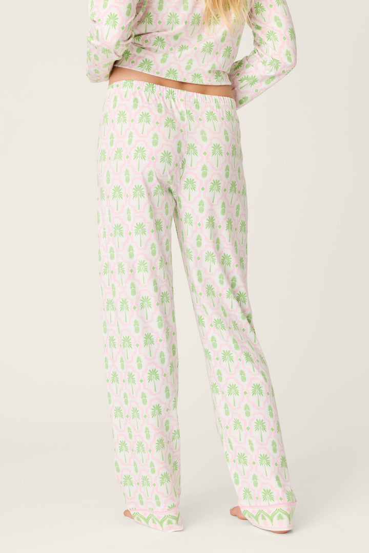 A person faces away, wearing P.J. Salvage Playful Prints Island Time Open Leg PJ Pants with a matching long-sleeved palm tree top. The relaxed ivory set pairs effortlessly with their blonde hair for an easy, breezy vibe.