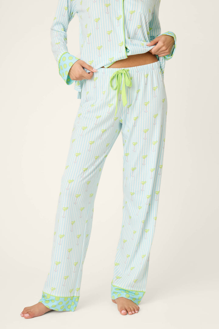 A person stands barefoot on a white background wearing the P.J. Salvage Playful Prints Island Time Short PJ Set, featuring light blue striped cotton-modal jersey fabric with small green prints and a green ribbon drawstring. Face not visible.