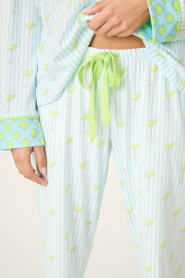 Wearing the P.J. Salvage Playful Prints Island Time Short PJ Set, featuring blue and white stripes, margarita glass pattern, lime green accents, and a waistband tied with a green ribbon. One hand is near the ribbon-tied waistband.