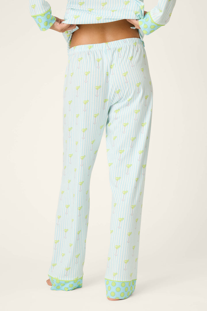 Shown from the back, a person wears P.J. Salvage’s Playful Prints Island Time Short PJ Set—light blue and white vertical stripes with light green accents and wide polka dot cuffs in cotton-modal jersey, plus a matching slightly cropped top.