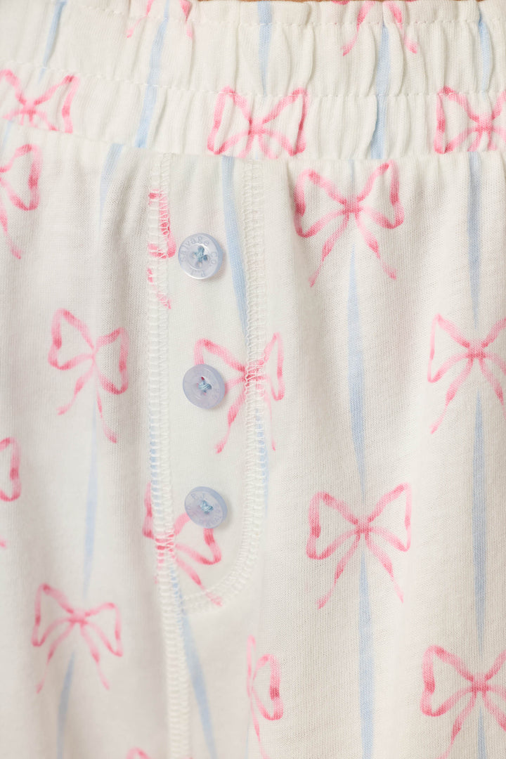 White cotton-modal jersey with light blue stripes, pink bow motif, and three light blue buttons; soft and cozy texture.