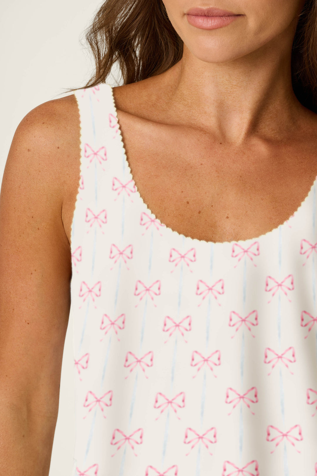 White fabric with a scalloped edge, decorated with small pink bows and thin blue lines.