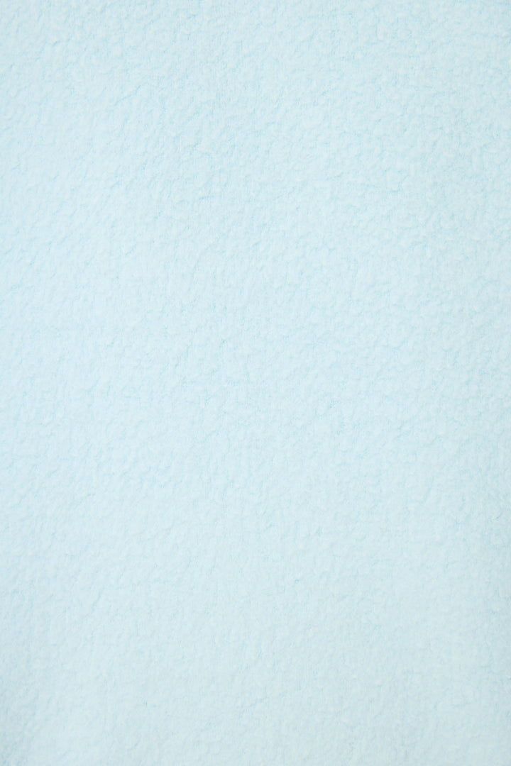 A close-up of the Pupcation Palms Vacay Pullover Sweater by P.J. Salvage, featuring a textured, light blue surface with cloud-like shading and a slightly uneven finish.