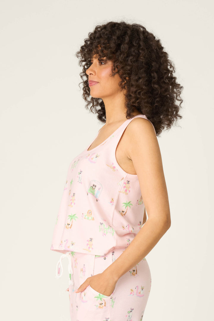 A woman with curly hair stands in profile, wearing the P.J. Salvage Pupcation Palms Sunnies & Sunshine Tank Top, facing left against a plain light background.