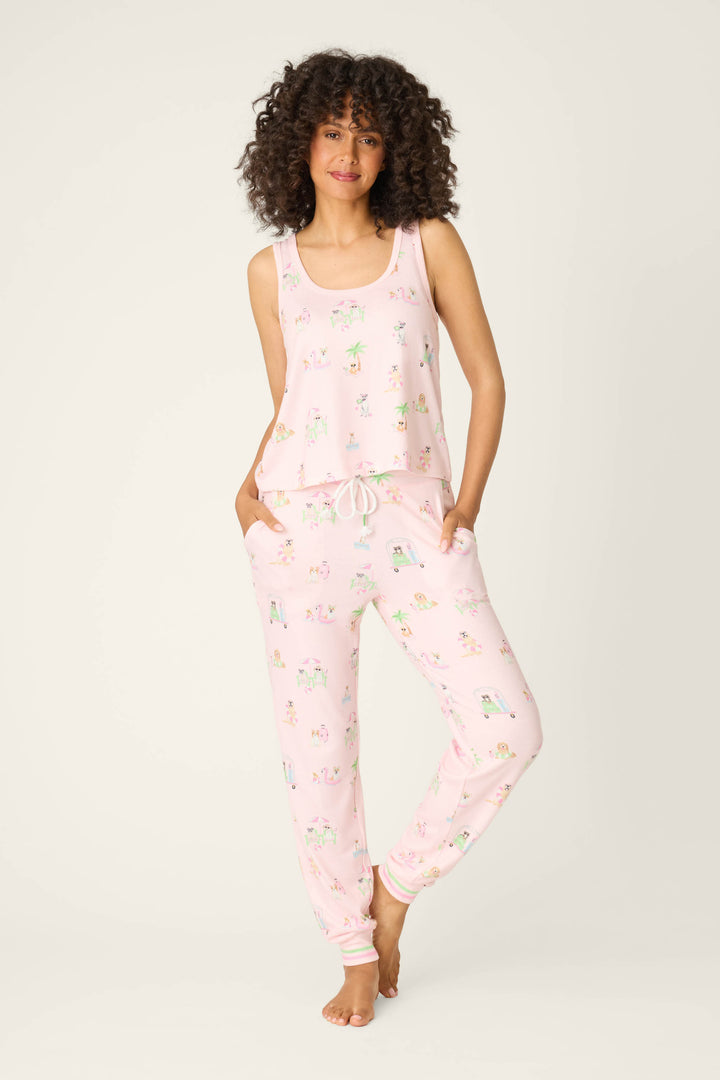 A person with curly hair stands barefoot, facing forward against a plain light background, wearing the P.J. Salvage Pupcation Palms Sunnies & Sunshine Tank Top with their hands in the pockets.