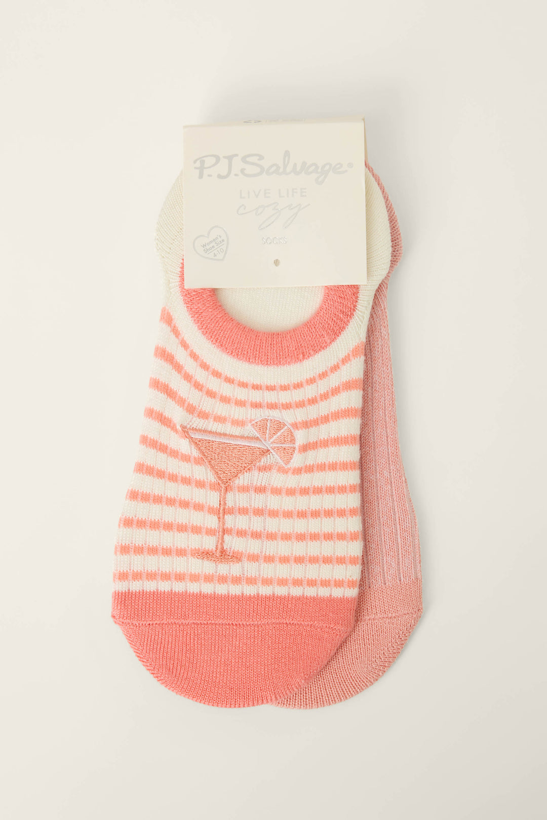 The P.J. Salvage Paloma Mama Sweet Sips 2-Pack No Show Sock Liners includes one pink and white striped sock with a cocktail glass design and one solid pink sock, both with branded cardboard tags.