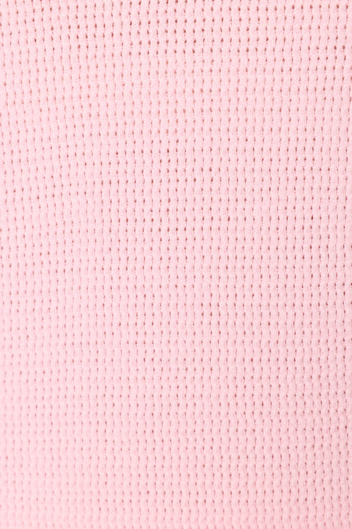 Close-up of the Roses Are Pink Rosé All Day Snuggle Sweater by P.J. Salvage, highlighting its pink waffle knit fabric with a grid-like textured pattern formed by small, evenly spaced rectangular indentations.