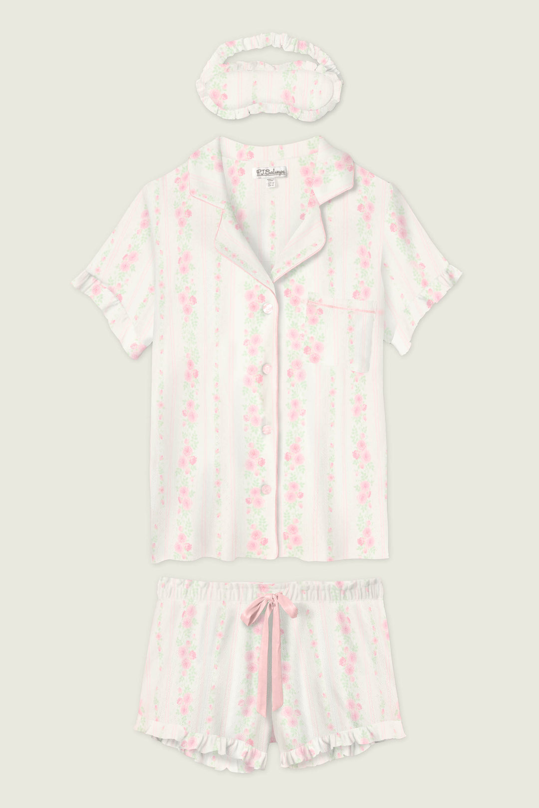 The P.J. Salvage Roses Are Pink Petal Dream Pointelle 3-Piece PJ Set includes a short-sleeved button-up top, matching shorts with a pink ribbon, and a ruffled sleep mask—all in pink and white vertical stripes with a floral motif.