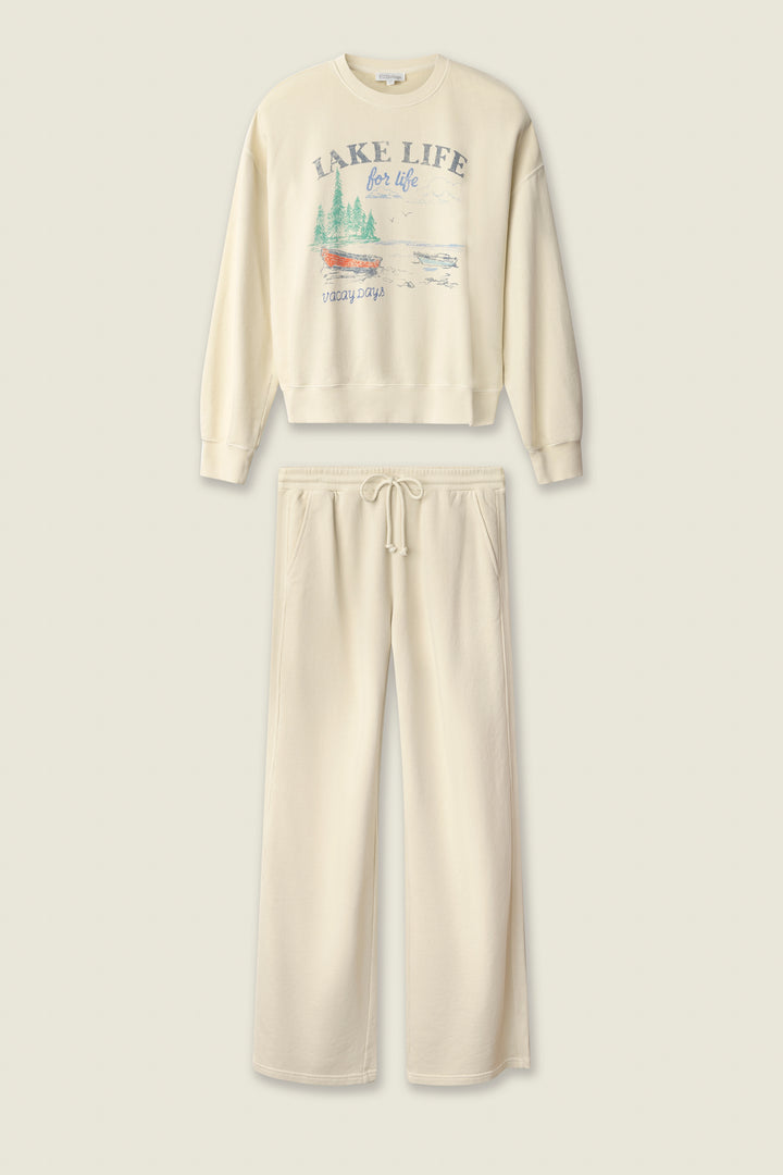 The Washed Away Lake Life For Life Long Lounge Set by P.J. Salvage includes a cream French terry crewneck with a lake-inspired graphic and matching wide-leg drawstring sweatpants for cozy comfort.