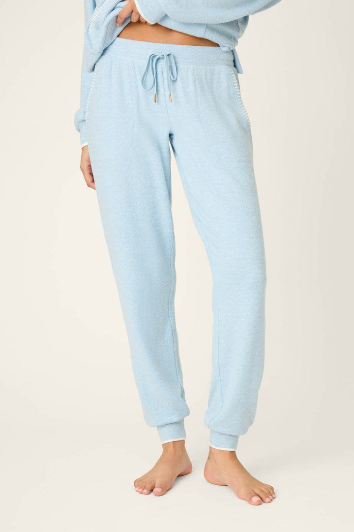 A person stands barefoot in P.J. Salvage Western Blooms Dream Blue Banded Pants, hands partly visible, wearing a matching sweatshirt. The photo is cropped above the shoulders and set against a plain background.