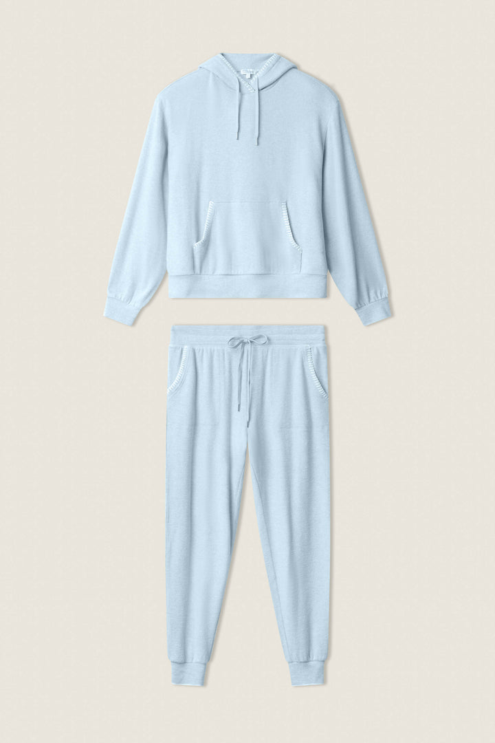 The P.J. Salvage Western Blooms Dream Blue Lounge Set features a hooded sweatshirt with front pockets and long sleeves, plus matching drawstring jogger pants with side pockets, all showcased on a neutral background.
