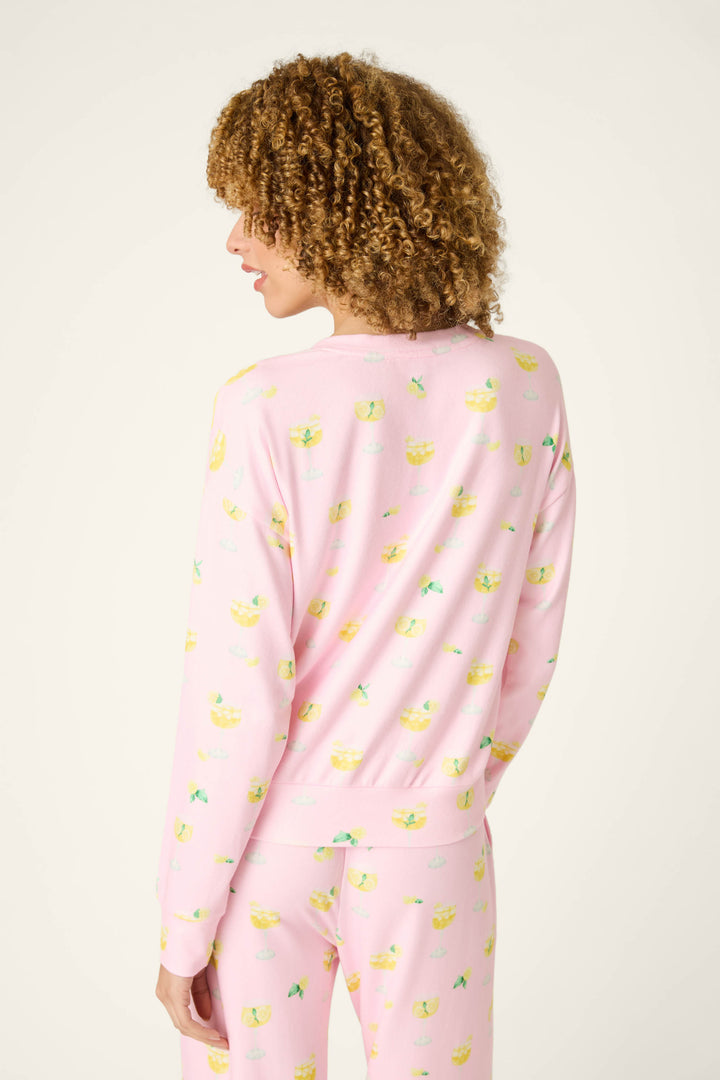Fabric with a playful yellow pattern on a light pink background, shown against a plain, light setting.