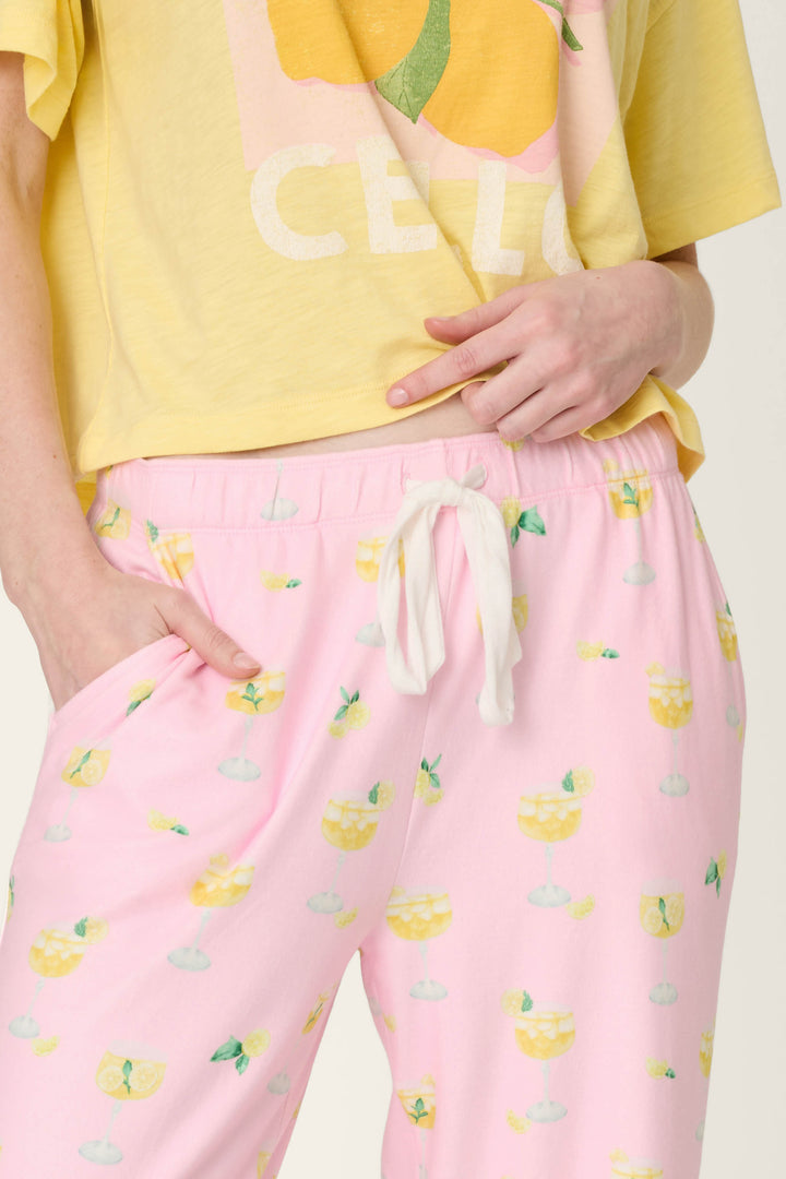 Light pink fabric with a repeating pattern of yellow drinks, lemon slices, and mint leaves.
