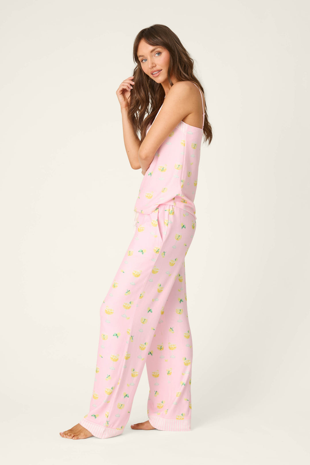 Pink fabric with a lively yellow and green fruit pattern; smooth texture, vibrant colors, playful and summery in appearance.