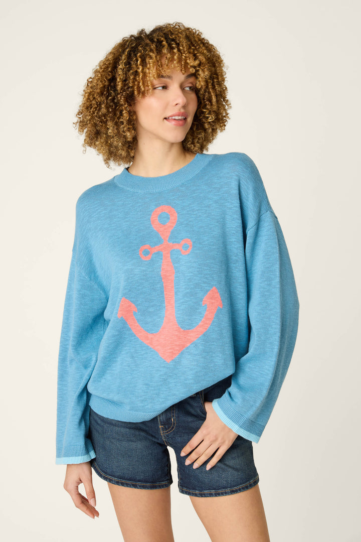 A loose blue fabric with a prominent large pink anchor design, shown next to dark denim on a plain light background.