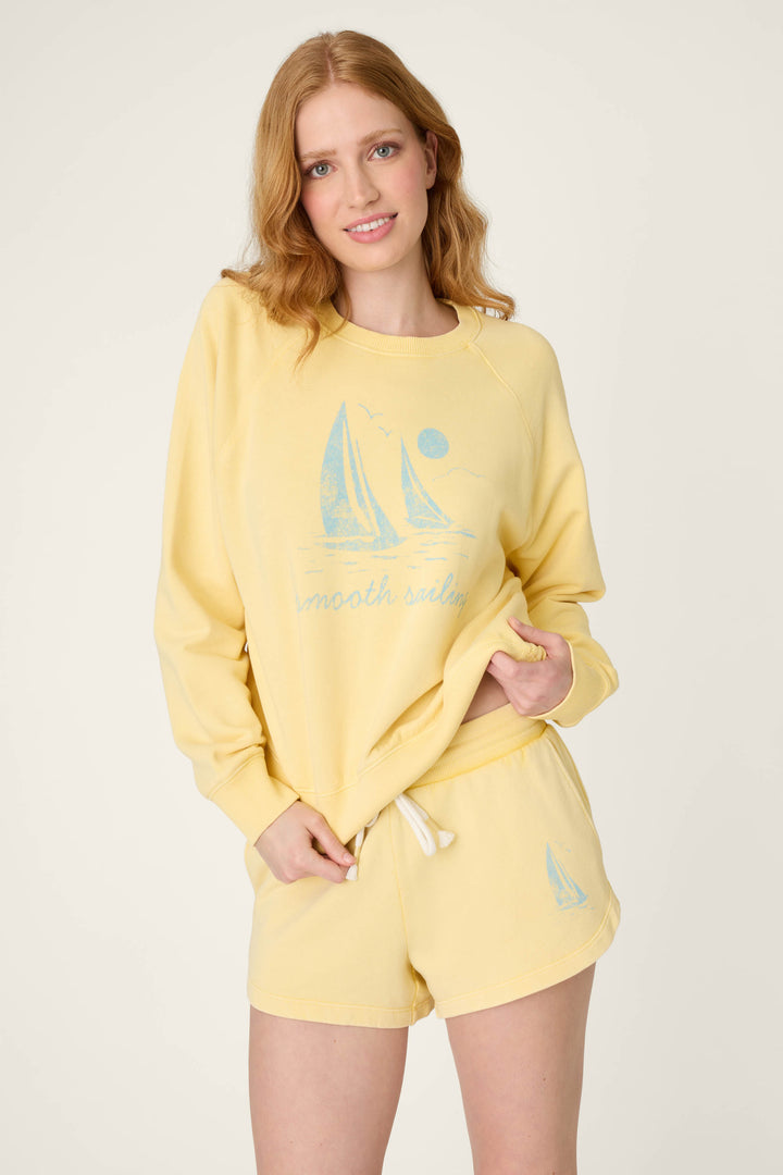 Light yellow fabric with a blue sailboat graphic and the words “smooth sailing” printed on it.
