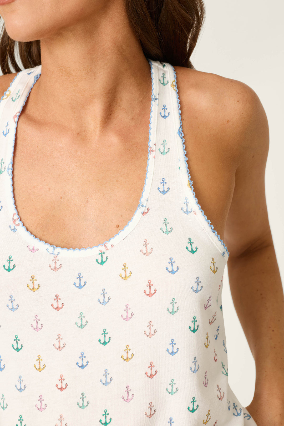 White fabric with blue trim and a colorful anchor pattern; smooth texture, bright and playful nautical design.