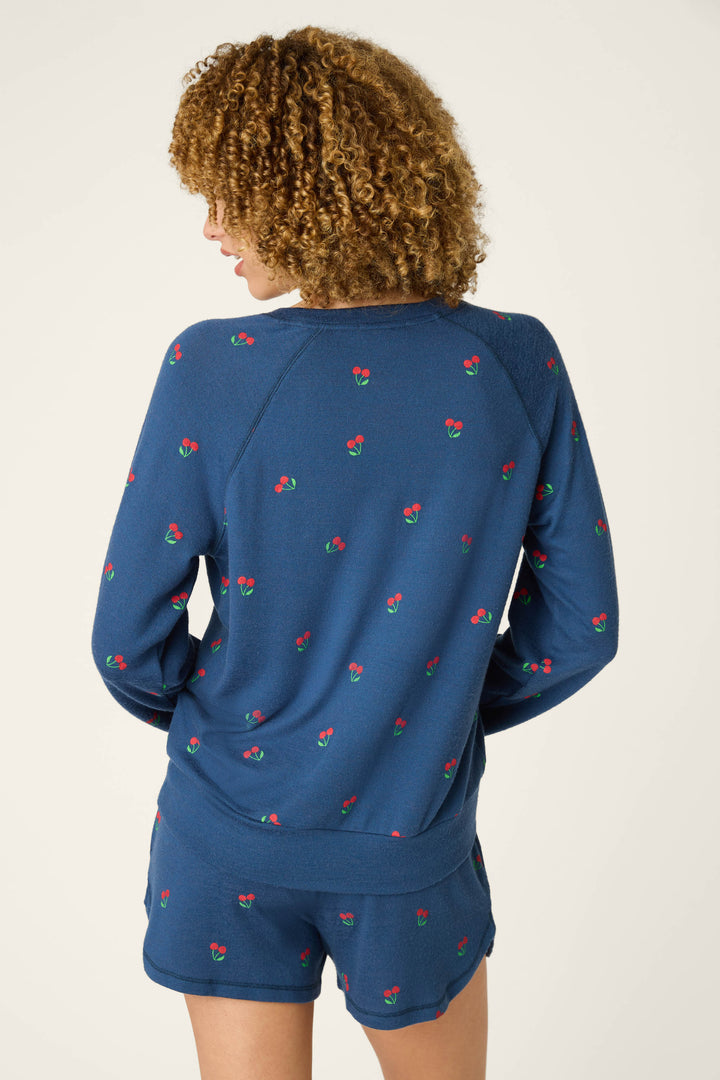 Fabric is true navy blue with a scattered pattern of small red and green cherries; appears soft, smooth, and relaxed.