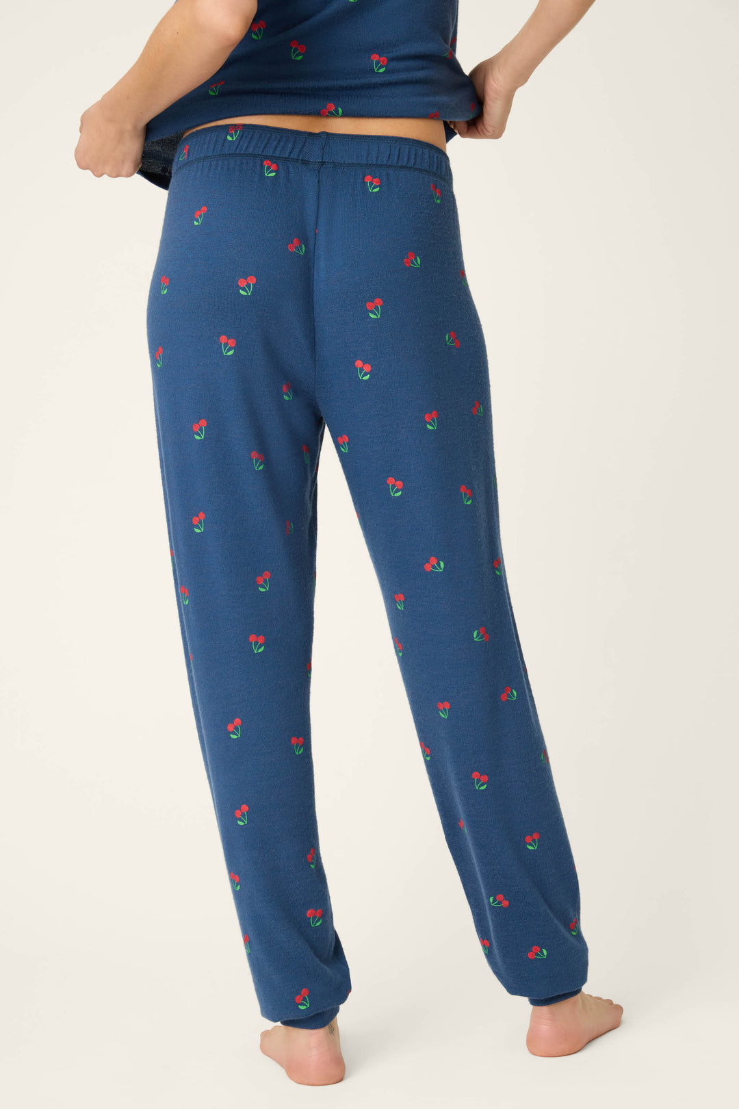 Blue fabric with a small red cherry print pattern on a navy background; texture appears smooth and soft.